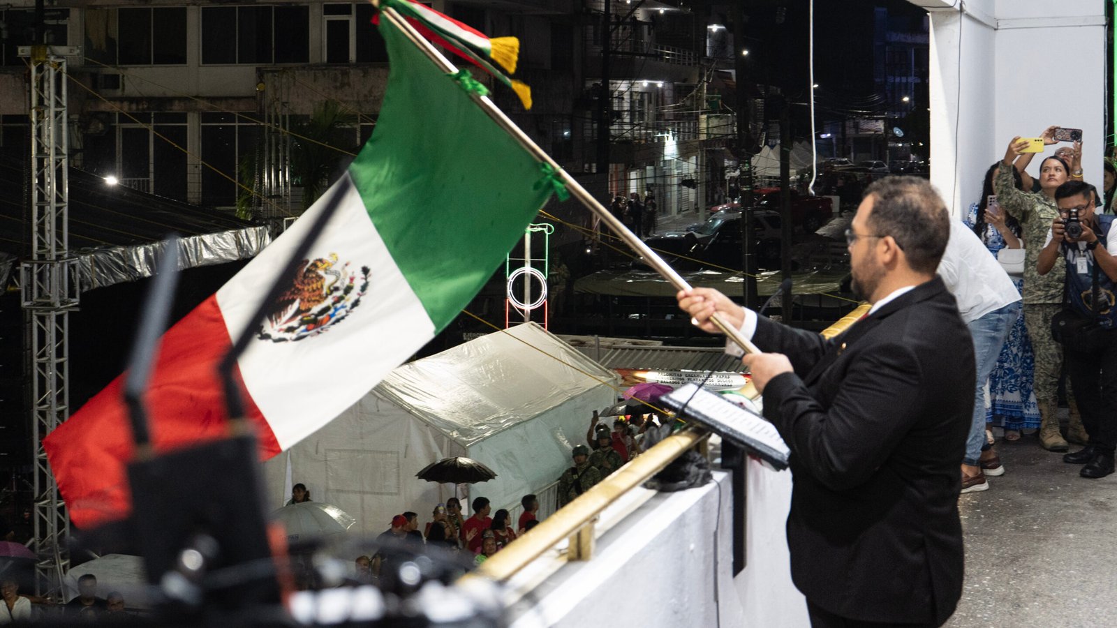 El alcalde Jesús Fomberoza ondea la Bandera Nacional durante el Grito de Independencia en la Plaza Cívica de Tuxpan.